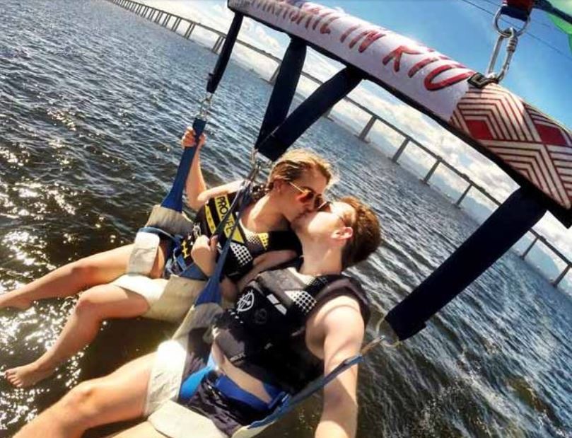 Casal voando de Parasail com a ponte Rio-Niterói ao fundo